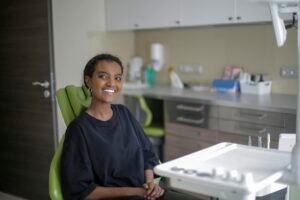 Happy woman sitting in a dental chair during a clinic visit, showcasing a cheerful and relaxed demeanor.